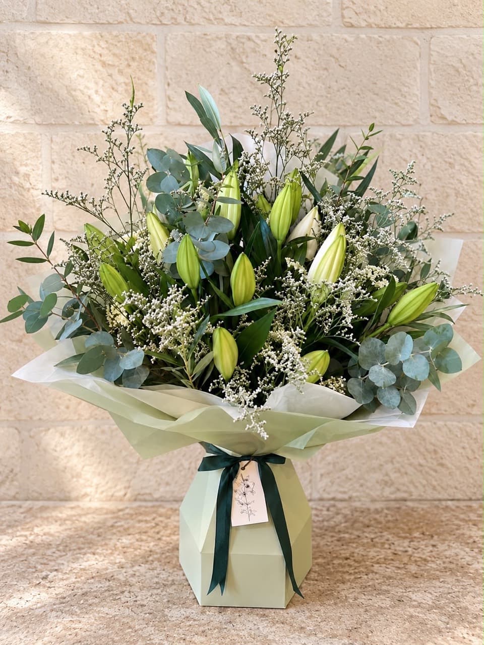 A Bloemist lily bouquet with eucalyptus and delicate white flowers in a pale green gift box