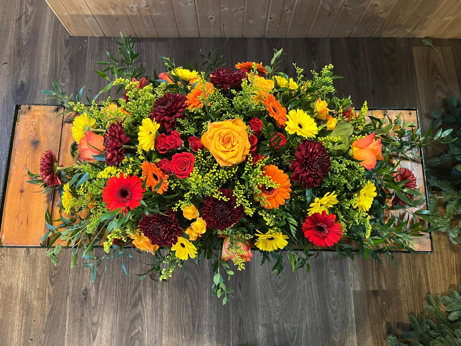 A vibrant tribute with orange and yellow roses and red flowers