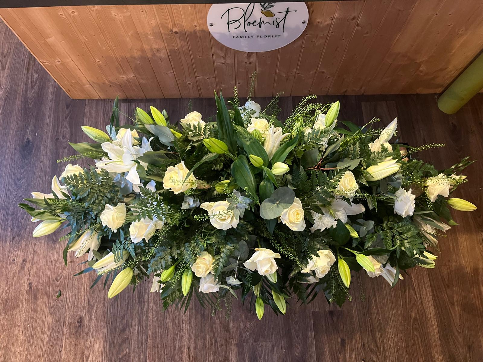 A white lily and cream rose casket spray