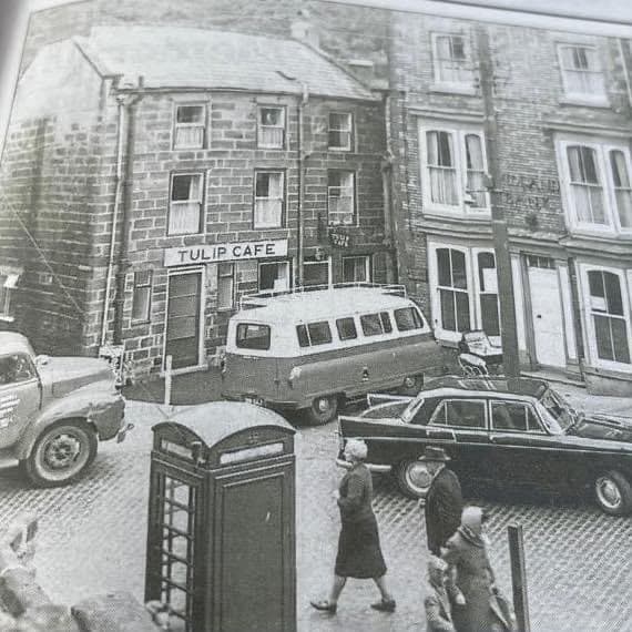 An old street photograph showing the Tulip Cafe, cars and a telephone box