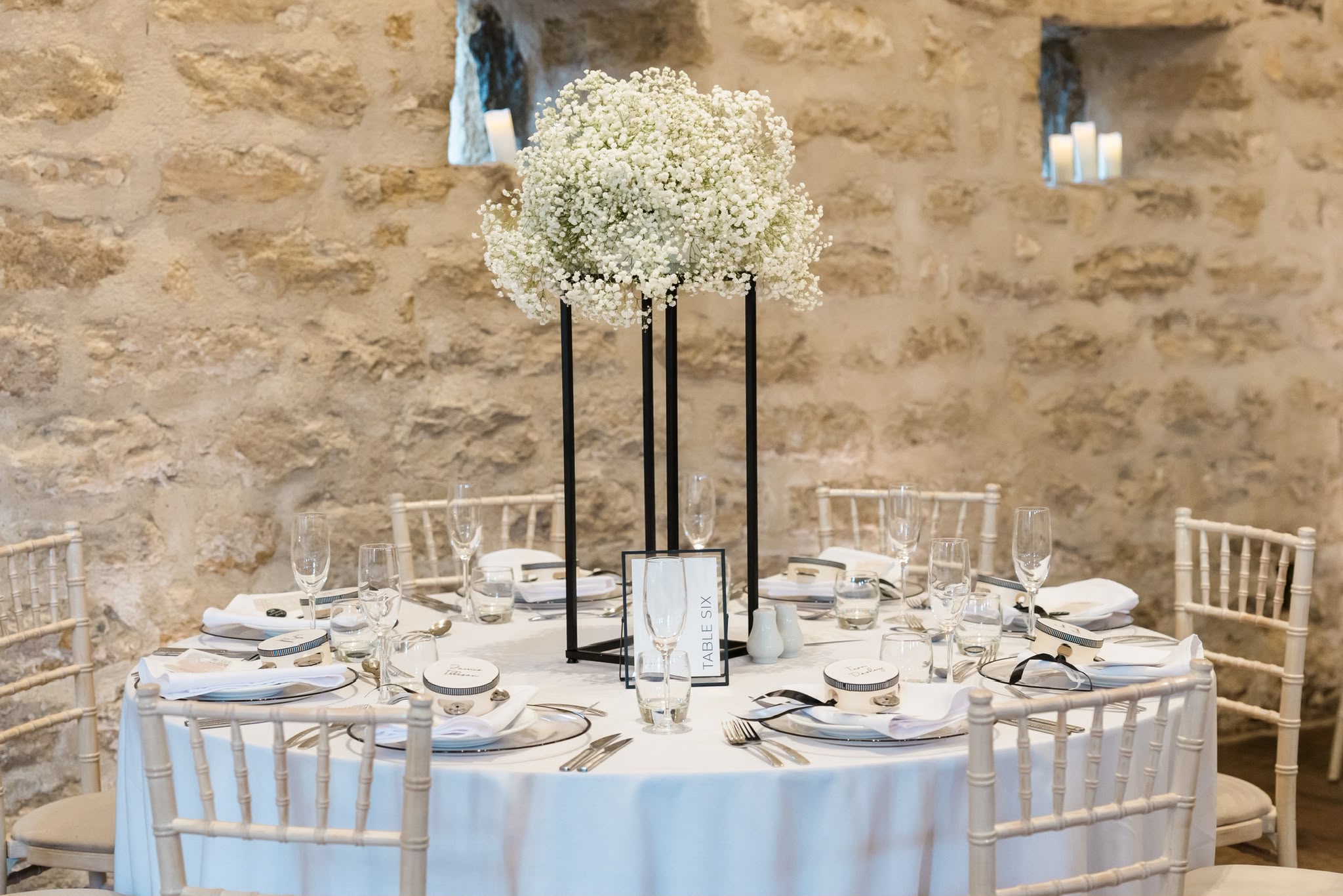 A tall white floral centrepiece above a wedding reception table