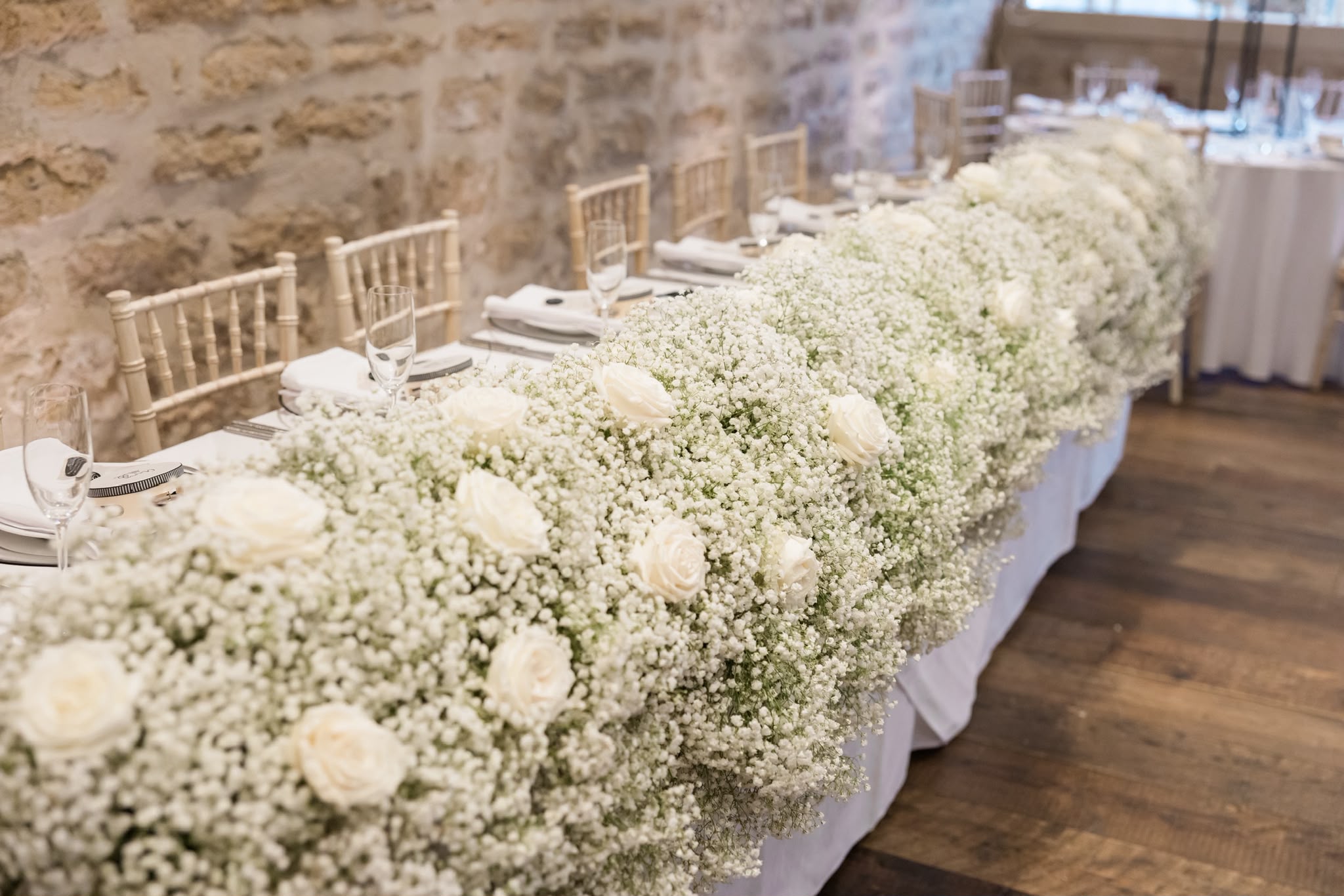 An abundant white floral garland along a wedding reception table